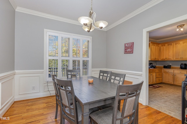 dining area with an inviting chandelier, light hardwood / wood-style flooring, and ornamental molding