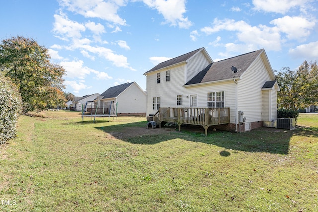 rear view of property with cooling unit, a yard, a deck, and a trampoline