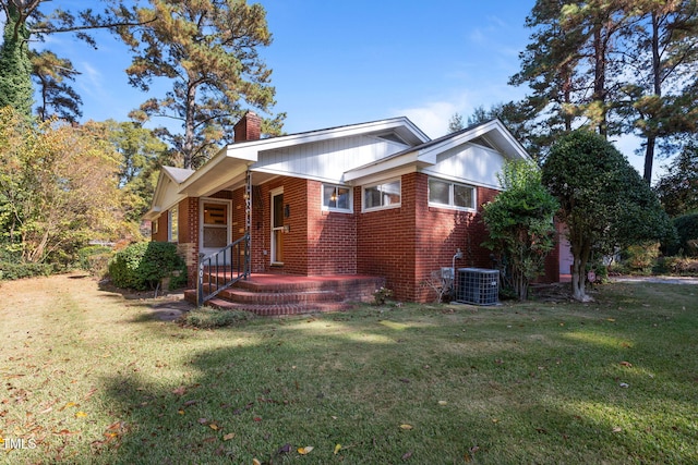 view of front of home with a front lawn, central air condition unit, and covered porch