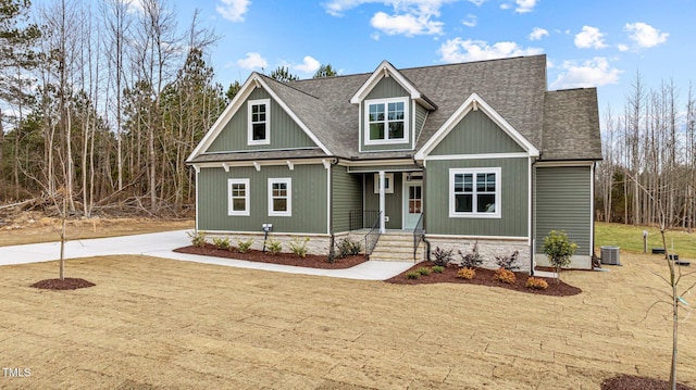 craftsman inspired home with central air condition unit and a front lawn