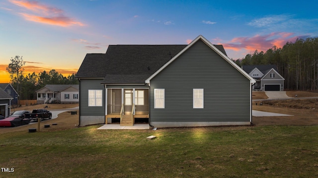 back house at dusk featuring a lawn