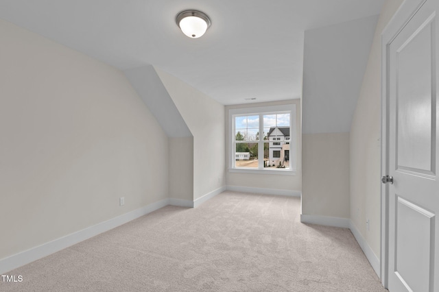 bonus room with vaulted ceiling and light colored carpet