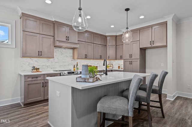 kitchen with extractor fan, backsplash, pendant lighting, stainless steel range oven, and a kitchen island with sink