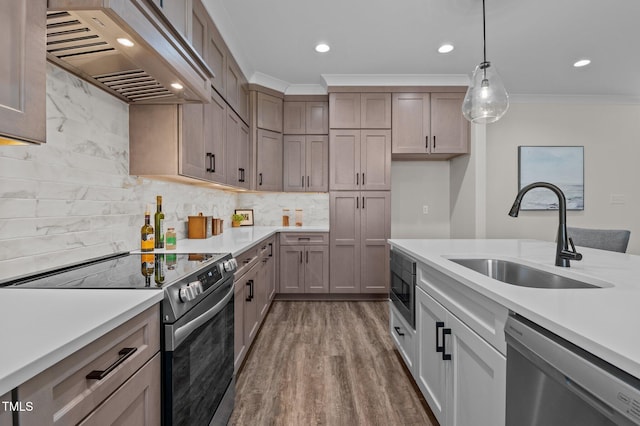 kitchen featuring sink, premium range hood, pendant lighting, crown molding, and stainless steel appliances