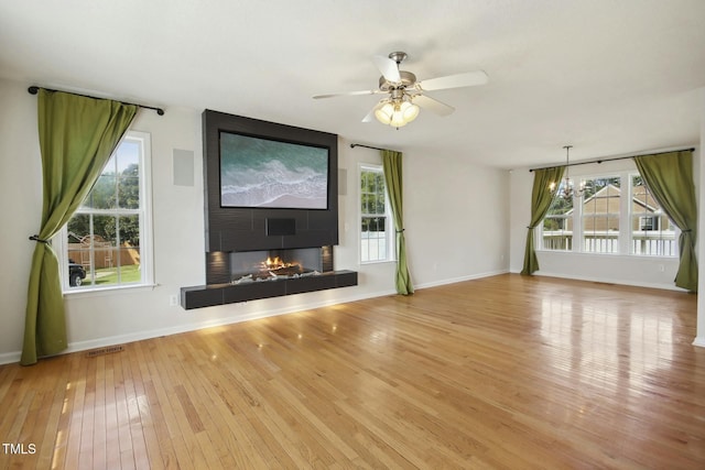 unfurnished living room featuring plenty of natural light, a tiled fireplace, and light hardwood / wood-style flooring