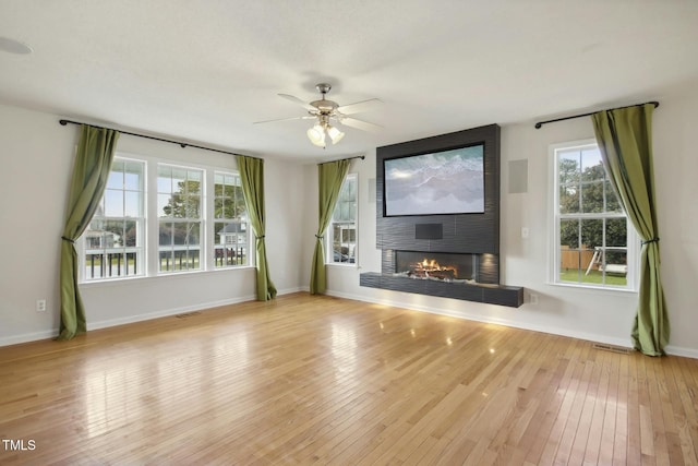 unfurnished living room featuring a fireplace, ceiling fan, and light hardwood / wood-style flooring