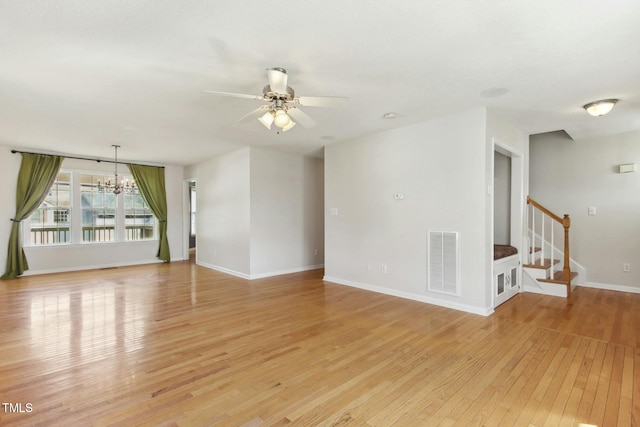 unfurnished living room with ceiling fan with notable chandelier and light hardwood / wood-style flooring