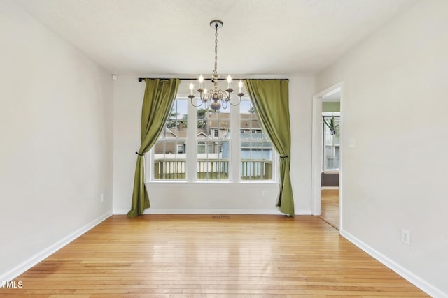 unfurnished dining area featuring light wood-type flooring and a notable chandelier