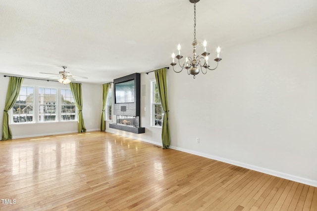 unfurnished living room with ceiling fan with notable chandelier and light hardwood / wood-style flooring