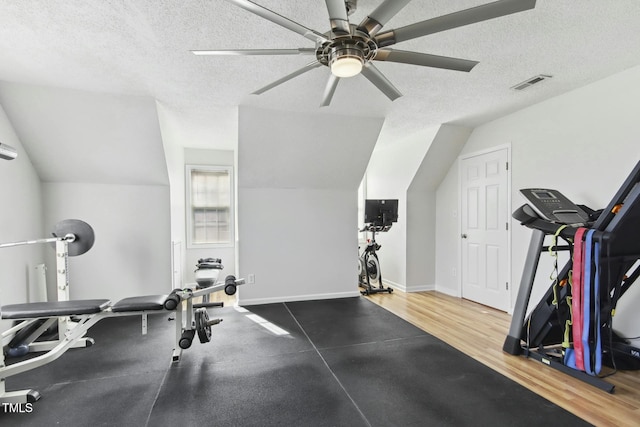 exercise area with wood-type flooring, a textured ceiling, lofted ceiling, and ceiling fan