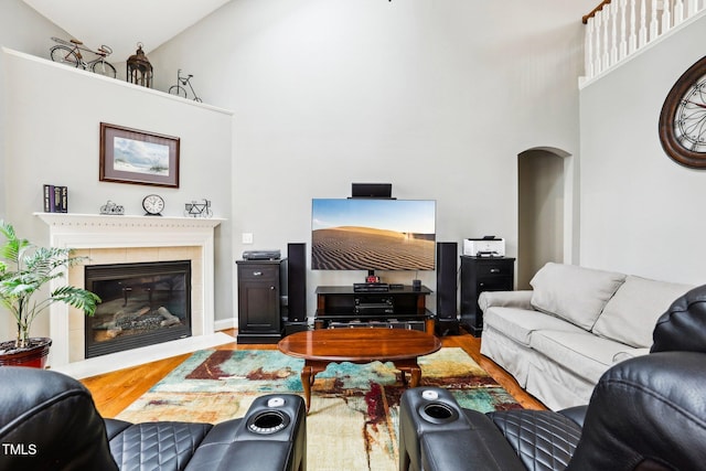 living room with hardwood / wood-style floors, high vaulted ceiling, and a tile fireplace