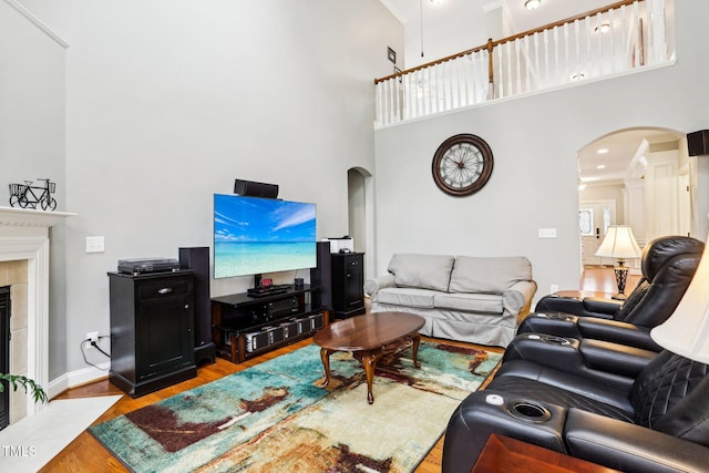 living room featuring a fireplace, a high ceiling, light hardwood / wood-style flooring, and crown molding