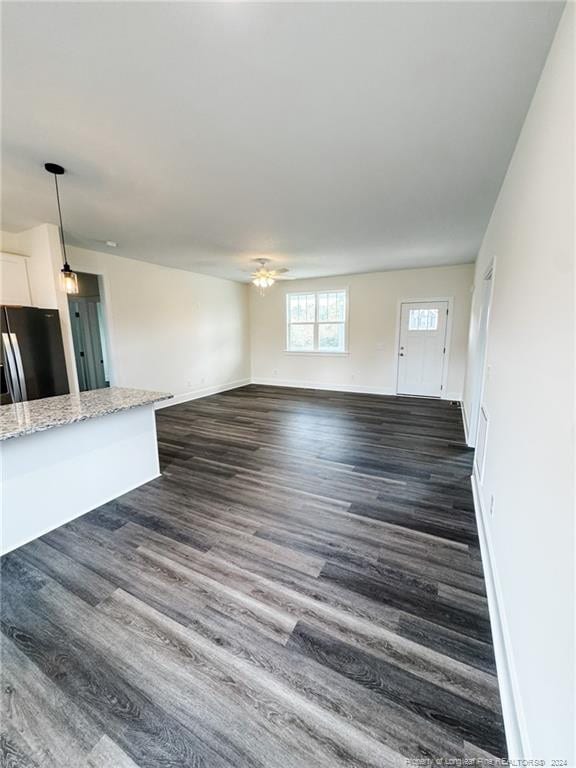 unfurnished living room featuring ceiling fan and dark hardwood / wood-style flooring