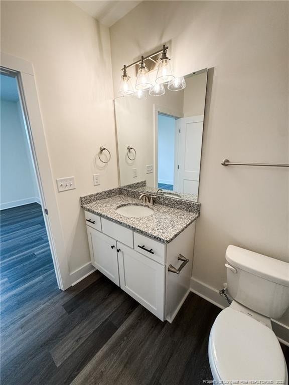 bathroom with hardwood / wood-style floors, vanity, and toilet