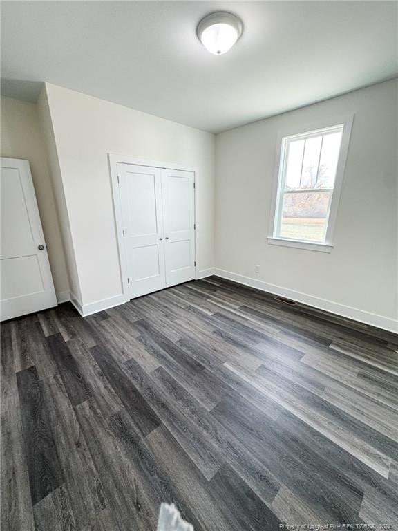 unfurnished bedroom featuring dark hardwood / wood-style flooring and a closet