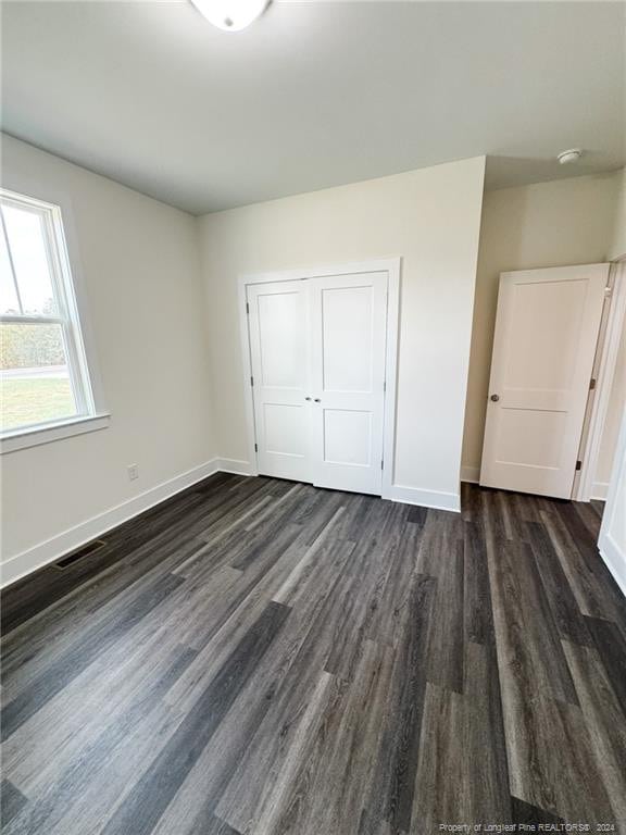 unfurnished bedroom featuring dark hardwood / wood-style floors and a closet