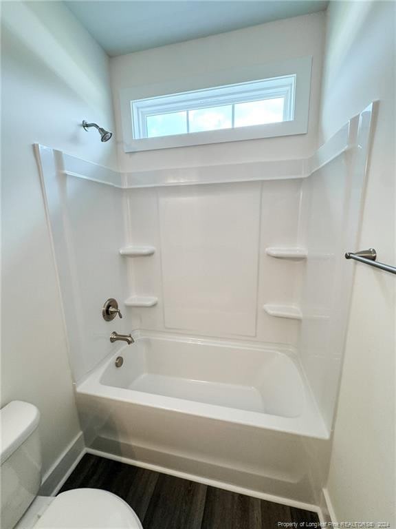 bathroom with hardwood / wood-style flooring, shower / tub combination, and toilet