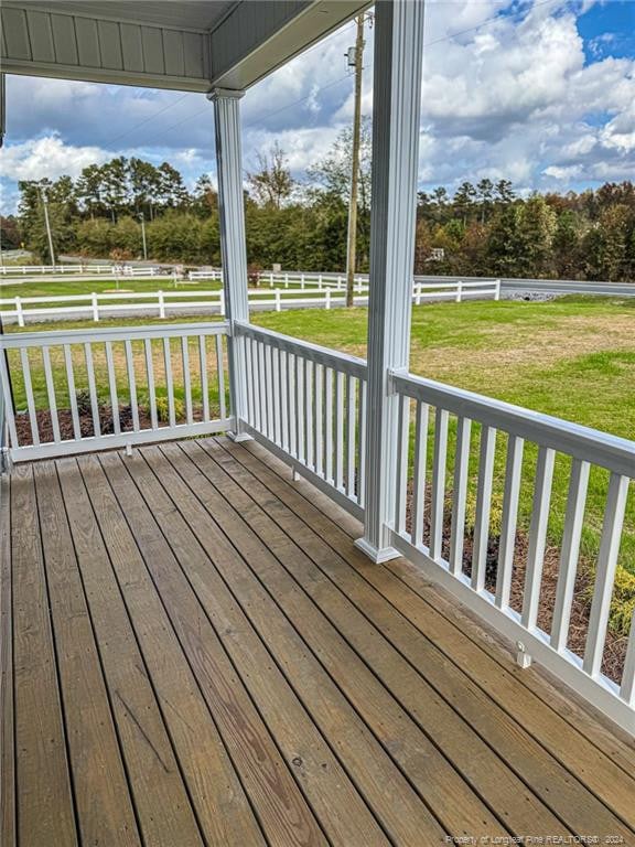 wooden terrace featuring a lawn and a rural view