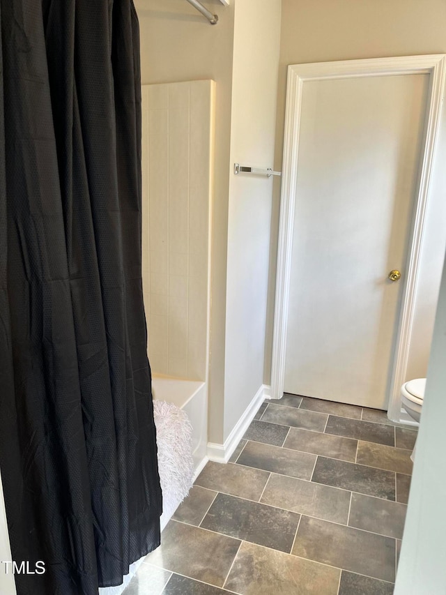 bathroom featuring toilet and shower / tub combo with curtain