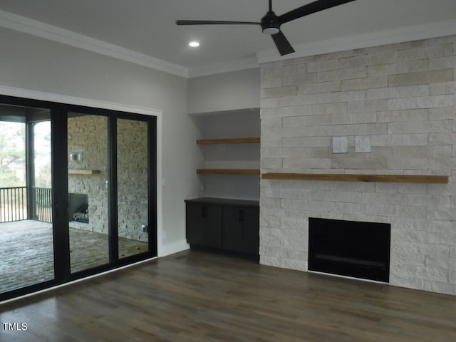 unfurnished living room with ceiling fan, a large fireplace, dark hardwood / wood-style flooring, and ornamental molding