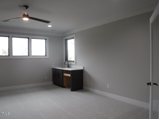 interior space featuring light colored carpet, ceiling fan, and sink