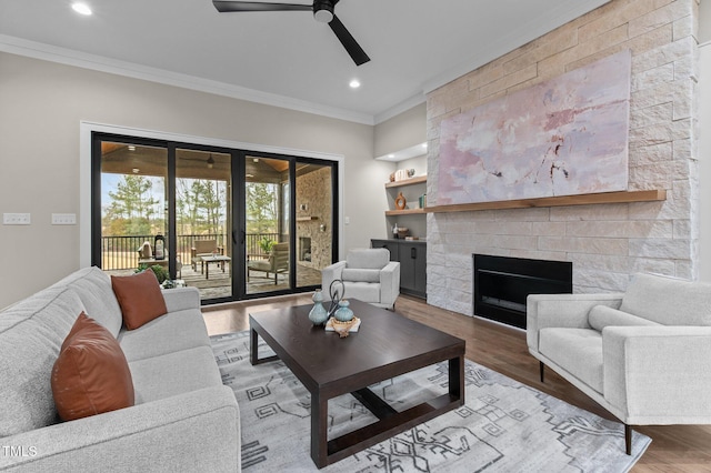 living room featuring crown molding, ceiling fan, hardwood / wood-style floors, a fireplace, and french doors