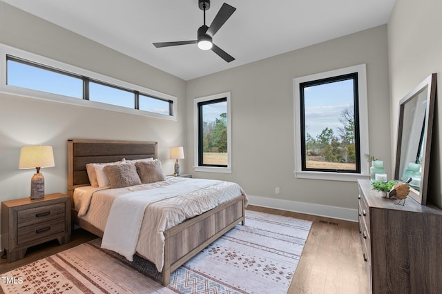bedroom with multiple windows, ceiling fan, and light wood-type flooring