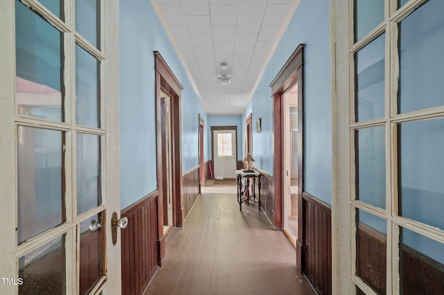 hallway featuring wooden walls, french doors, hardwood / wood-style floors, and crown molding