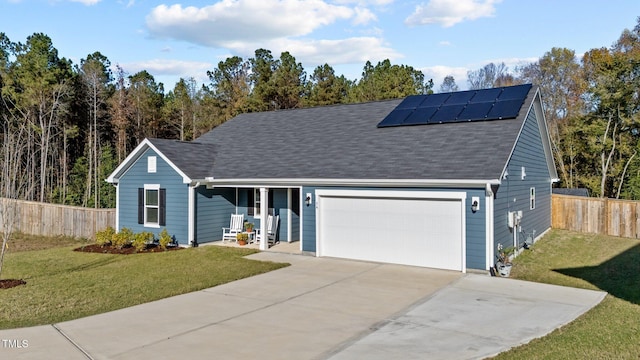 view of front of property featuring a garage, a front lawn, and solar panels