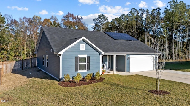 view of front of house featuring a garage, a front yard, and solar panels