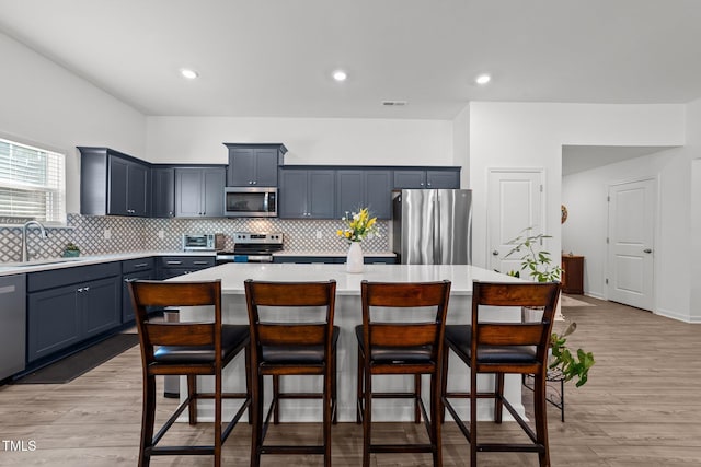 kitchen with a breakfast bar area, appliances with stainless steel finishes, a center island, and sink