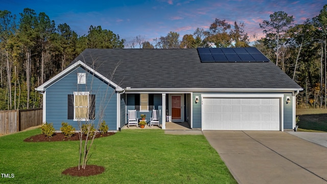 single story home with covered porch, solar panels, a yard, and a garage