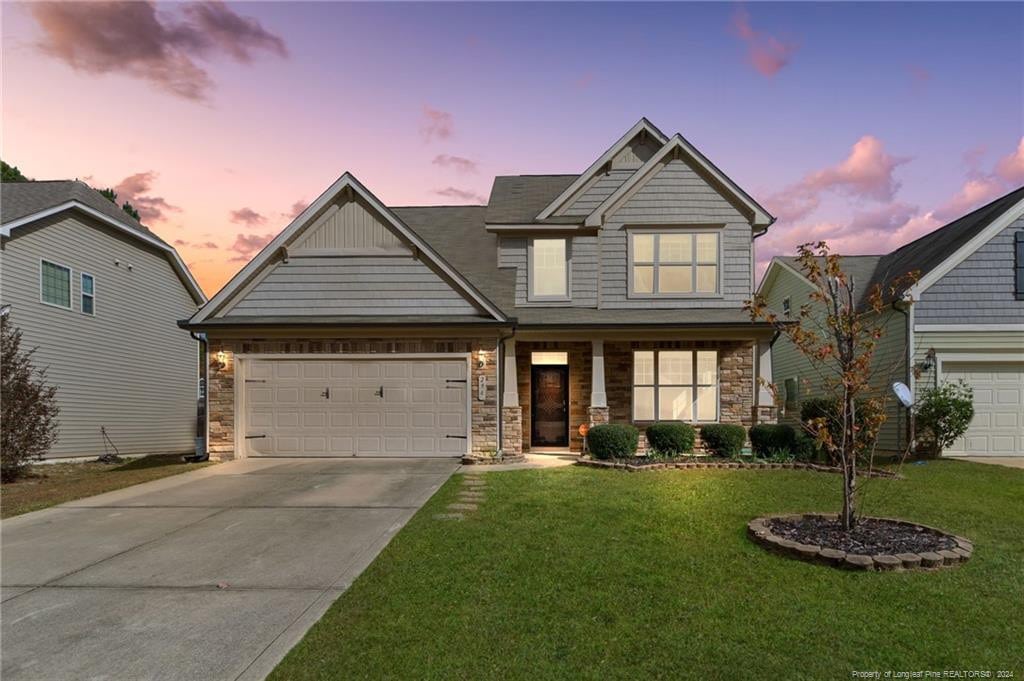 craftsman inspired home featuring a garage, a yard, and a porch