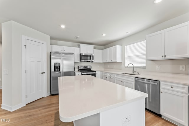 kitchen with light hardwood / wood-style flooring, white cabinetry, appliances with stainless steel finishes, and a center island