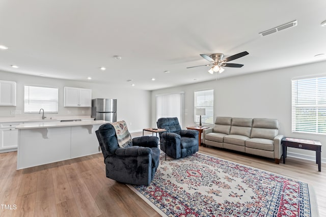 living room featuring a wealth of natural light, light hardwood / wood-style floors, ceiling fan, and sink