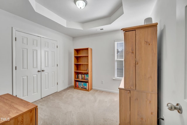 misc room featuring light carpet and a tray ceiling