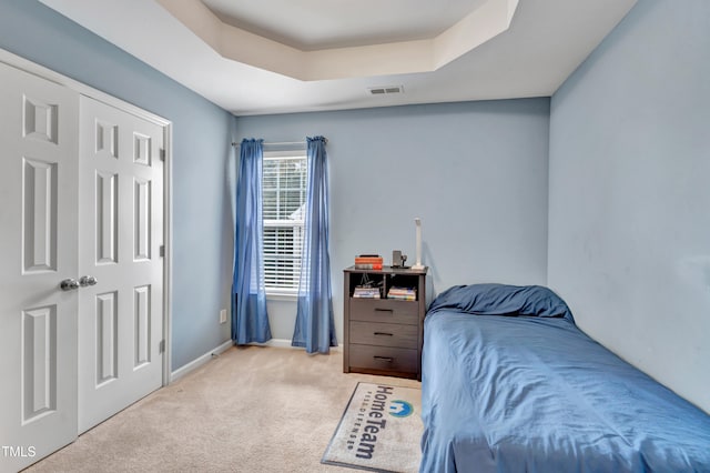 carpeted bedroom featuring a tray ceiling