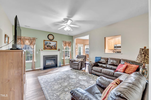 living room featuring ceiling fan, a healthy amount of sunlight, and light hardwood / wood-style flooring