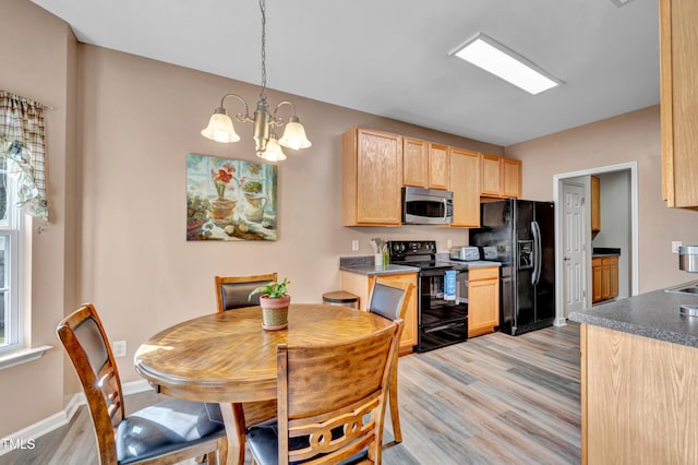 kitchen featuring an inviting chandelier, black appliances, light brown cabinets, light hardwood / wood-style flooring, and decorative light fixtures