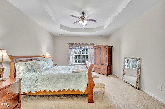 carpeted bedroom featuring a tray ceiling and ceiling fan