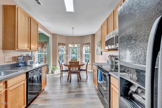 kitchen with an inviting chandelier, black appliances, light brown cabinets, pendant lighting, and light hardwood / wood-style flooring