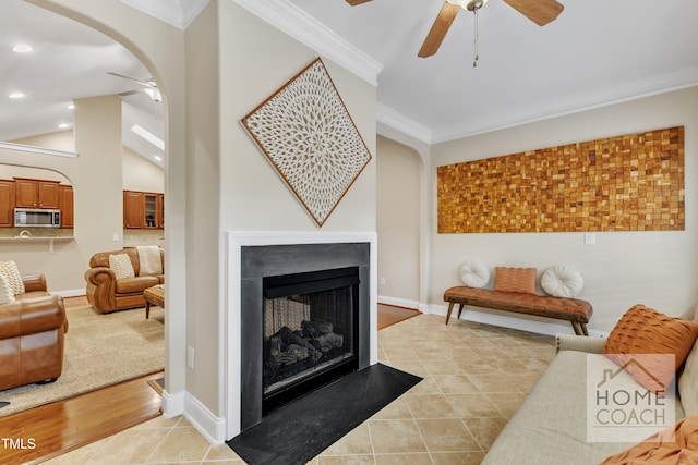 tiled living room with a multi sided fireplace, lofted ceiling, ceiling fan, and crown molding