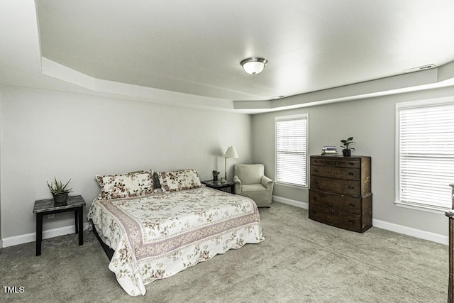 bedroom with light colored carpet and a tray ceiling