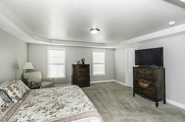 bedroom featuring light carpet and a tray ceiling