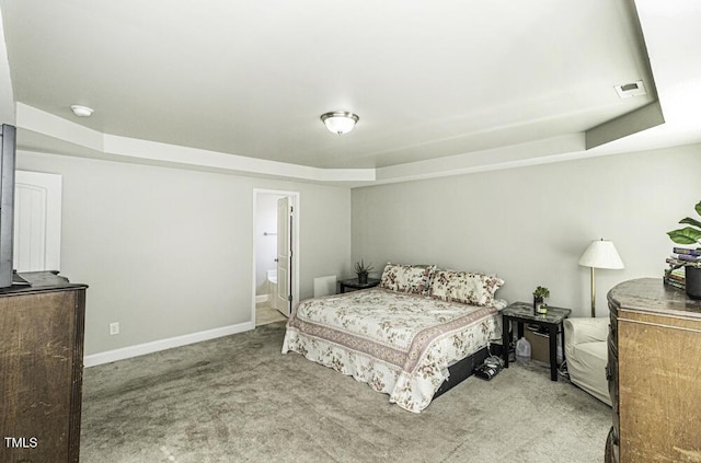 carpeted bedroom with a tray ceiling and ensuite bathroom