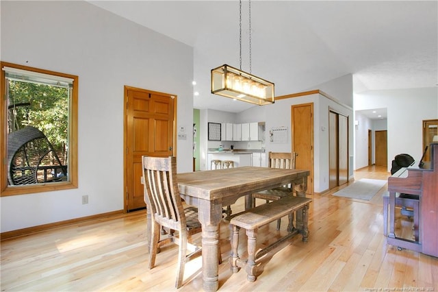 dining area featuring light hardwood / wood-style flooring and high vaulted ceiling