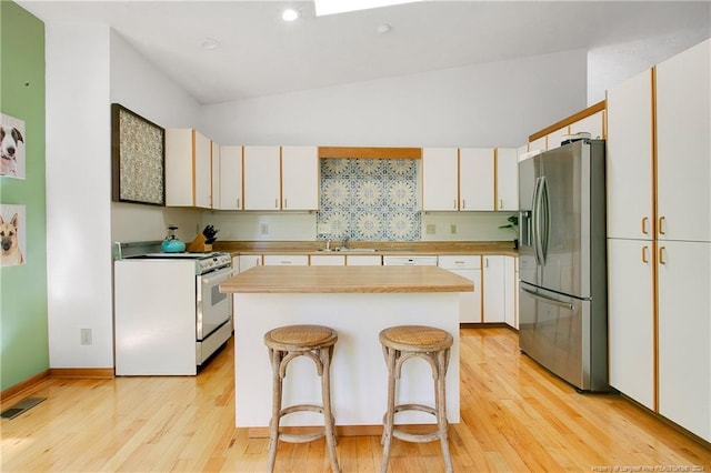 kitchen with stainless steel refrigerator with ice dispenser, white cabinetry, and white stove