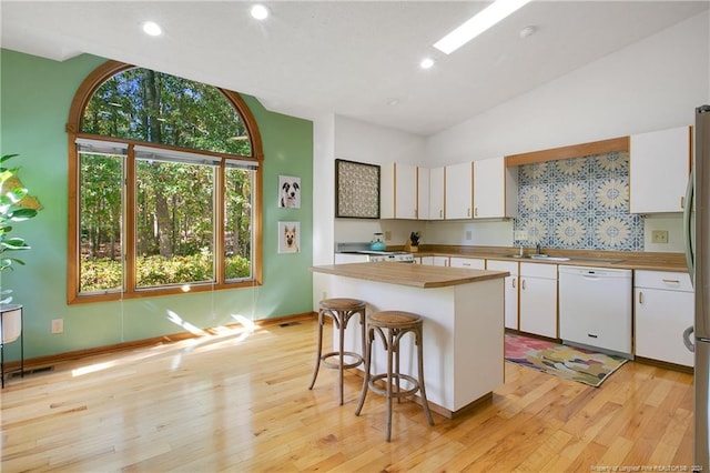 kitchen with dishwasher, lofted ceiling, white cabinets, and a center island