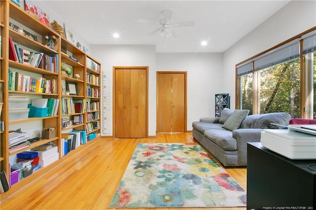 living area with wood-type flooring and ceiling fan