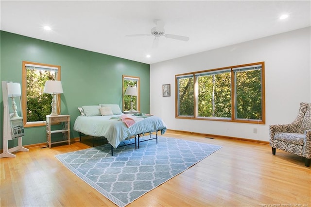 bedroom featuring multiple windows, ceiling fan, and light hardwood / wood-style flooring